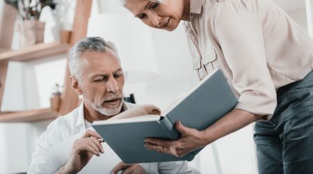 Senior business colleagues discussing book at office